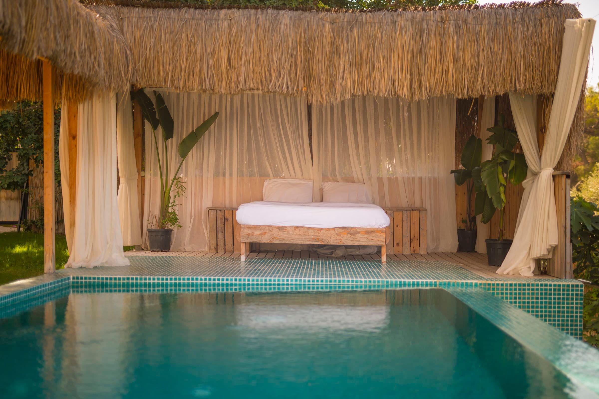 Kekik zur goldenen Stunde: Außenbett mit Vorhängen unter einem Schilfdach und privater Pool.