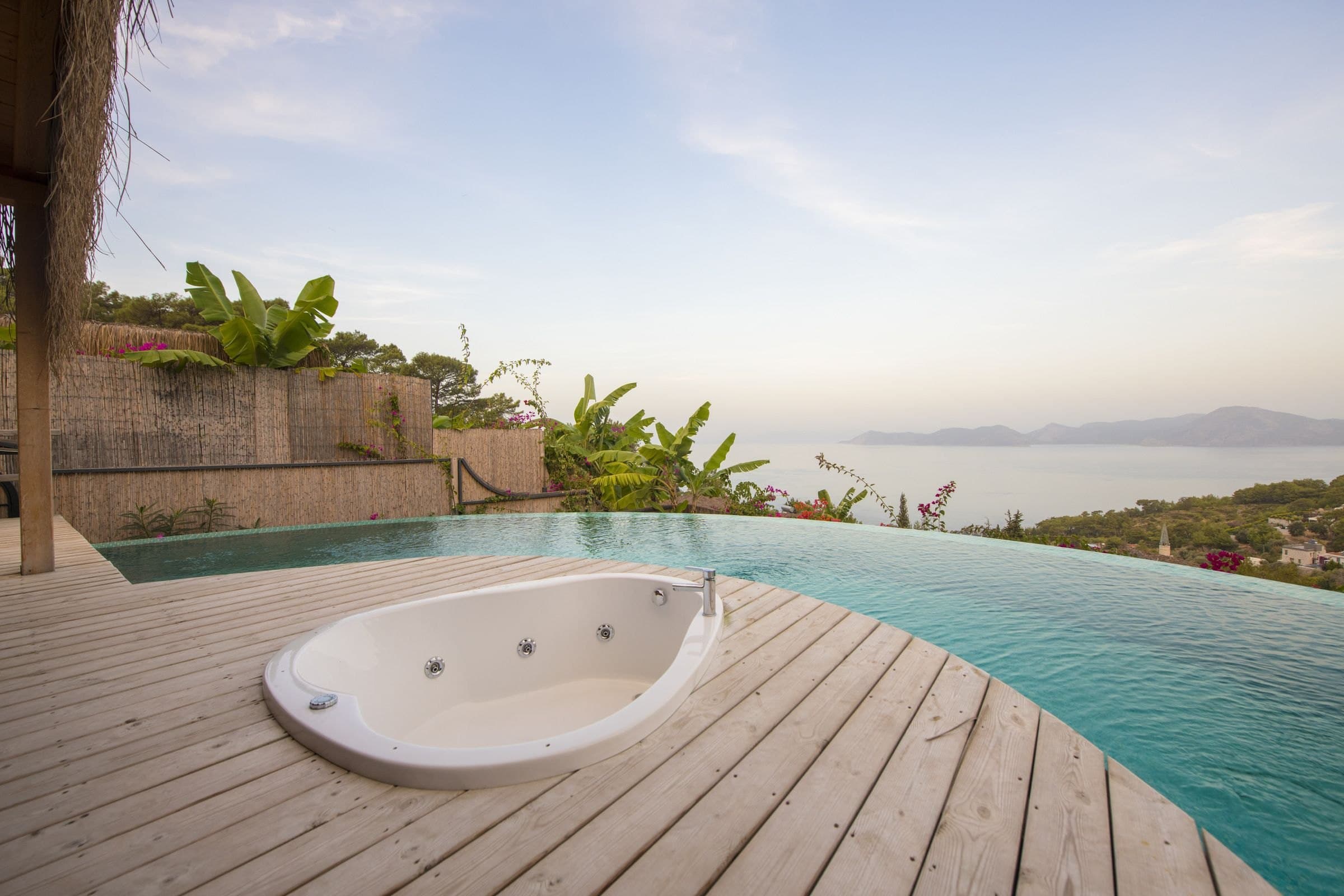 Ladin: eingelassener Whirlpool, Infinity-Kante und Meer in weichem goldenem Licht.