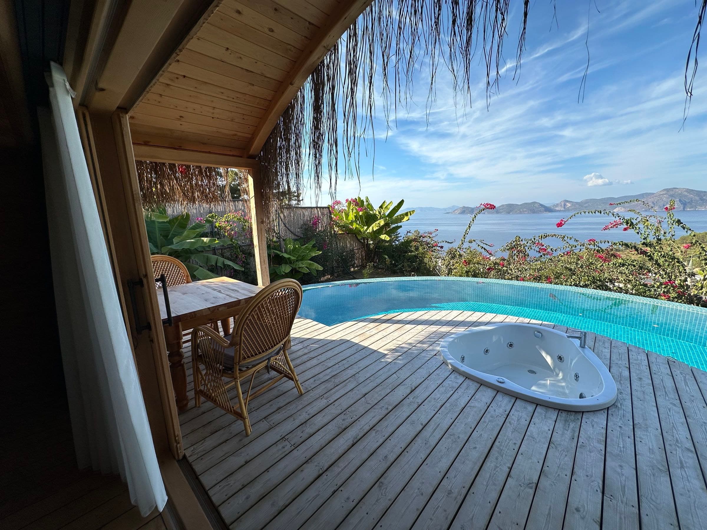 Mimoza: von der Veranda unter der Schilftraufe Tisch, herzförmiger Whirlpool, Infinity-Pool, Meer und Inseln.